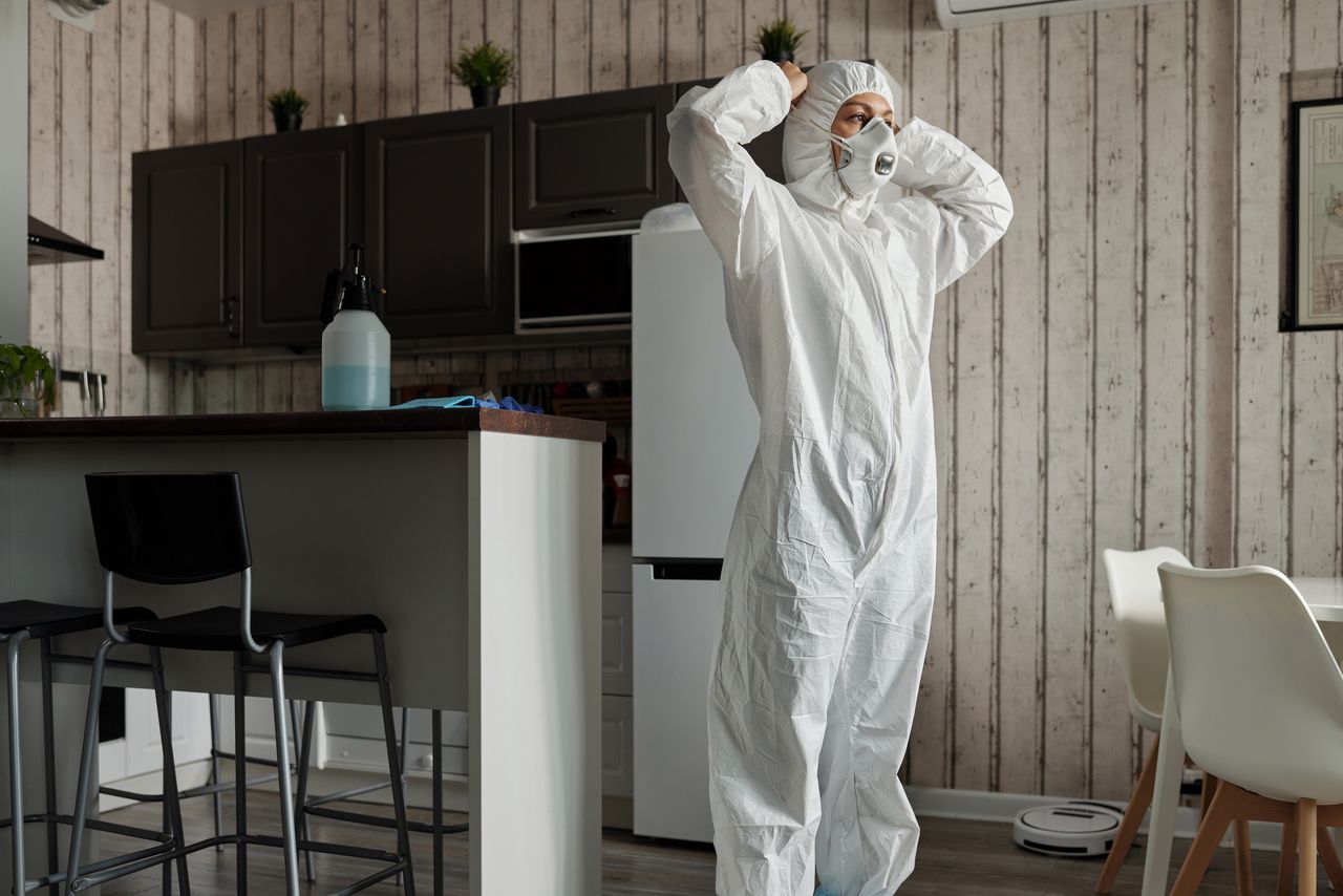 journey-01 Individual in protective gear standing in a contemporary kitchen setting during the day.